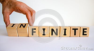 Finite or infinite symbol. Businessman turns wooden cubes and changes the word `finite` to `infinite`. Beautiful white table, Stock Photo
