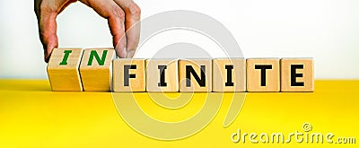 Finite or infinite symbol. Businessman turns wooden cubes and changes the word `finite` to `infinite`. Beautiful yellow table, Stock Photo