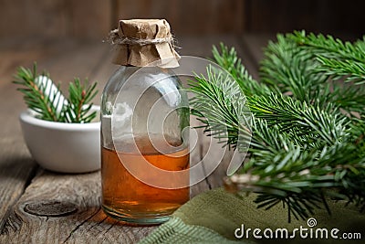 Fir aromatic oil. Pine essential oil in a transparent glass bottle. Coniferous tree branches and mortar. Stock Photo