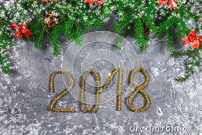 Fir branches with cones and red bows on top of a gray concrete background. New Year Christmas. Text 2018 of gold tinsel. Stock Photo