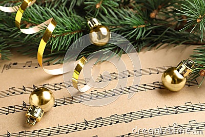 Fir branches, golden streamer and balls on Christmas music sheets, closeup Stock Photo