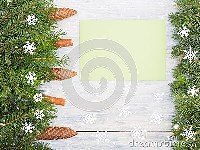 Fir tree branch with cones, cinnamon, green envelope, snowflake on white wooden background Stock Photo