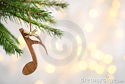 Fir tree branch with wooden note against blurred lights. Christmas music Stock Photo