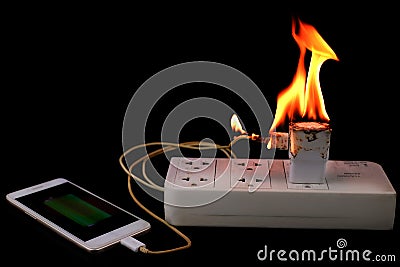On fire Adapter smart phone charger at plug in power outlet Stock Photo