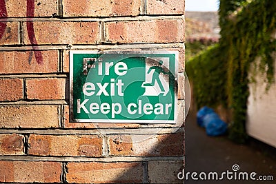 Fire Exit sign seen outside a business entrance, seen down a very narrow street. Editorial Stock Photo