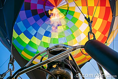 Fire from a gas burner in a hot air balloon. Hot gas inflates a bright, multi-colored balloon. Bottom view Stock Photo