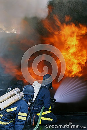 Fire men in action burning building Stock Photo