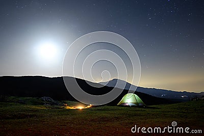 Fire at night, lighting tent and Etna Volcano under moon light Stock Photo