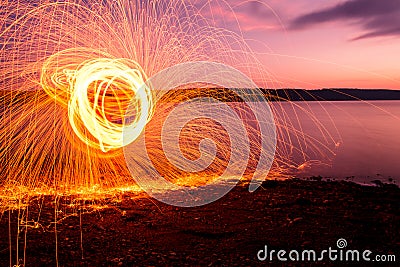Fire Poi at sunset on the lake Stock Photo