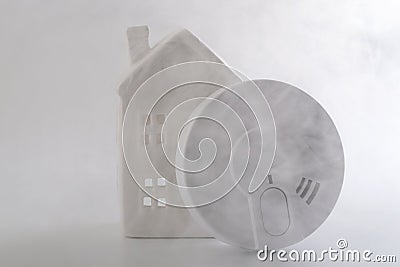 Fire prevention, home security and monitoring dangerous fumes conceptual idea with generic smoke detector and miniature house Stock Photo