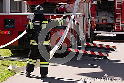 Fireman unwinds the hydrant near the fire truck Editorial Stock Photo