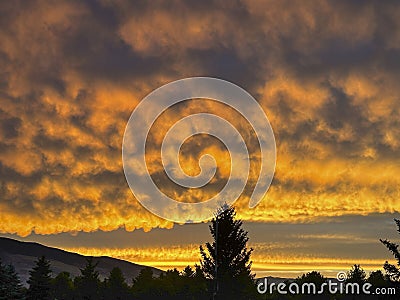 Fire in the sky or fiery clouds are seen as the sun sets over mountains in Wyoming Stock Photo