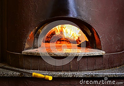 Fire stone stove oven for preparing traditional italian pizza. Fire wood burning in oven. Stock Photo