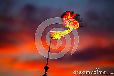 Fire torch at sunset sky with red clouds Stock Photo