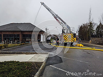 Fire truck uses its aerial hose to fight a devastating fire in a building housing a Starbucks store Editorial Stock Photo