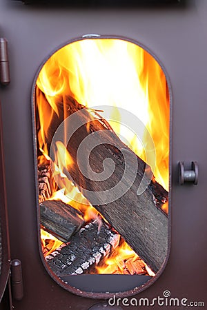 Fire-wood are burning in a fire-chamber of a stove with an opened door Stock Photo