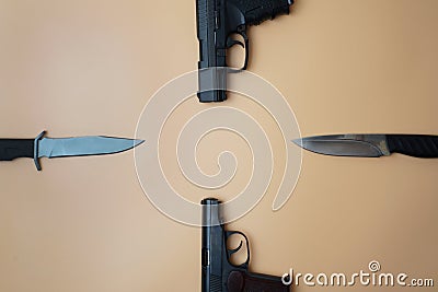 Firearms laid out along a circle. Three guns pistols, army knives close-up on a neutral beige background. copy space Stock Photo