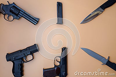 Firearms laid out along a circle. Three guns pistols, cartridges, army knives close-up on a neutral beige background. copy space Stock Photo