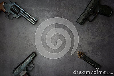 Firearms laid out along the line. Three guns pistols, cartridges close-up on a gray concrete background. copy space Stock Photo