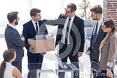 Fired employee with personal things saying goodbye to colleagues Stock Photo