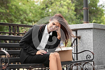 Fired office worker with personal stuff sitting on bench outdoors Stock Photo