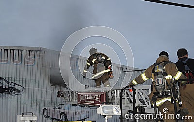 Firefighters climb a ladder truck to get a better position On fighting the fire at a warehouse in Hyattsville, Marylanda Editorial Stock Photo