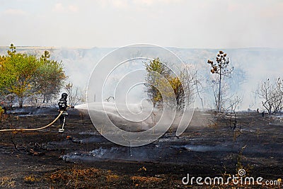 Firefighter extinguishes burning grass Stock Photo