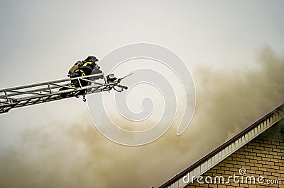 A firefighter puts out a burning building with height extension ladders Stock Photo