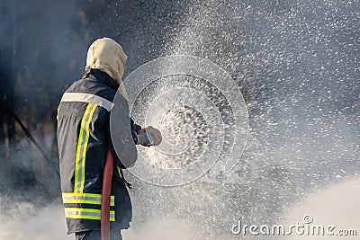 Firefighter spraying water from big water hose to prevent fire Stock Photo