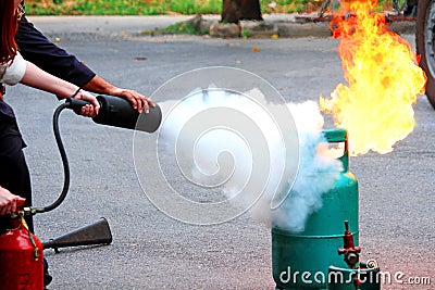 Firefighter teaching woman or man how to using fire extinguisher spraying form to fire Stock Photo