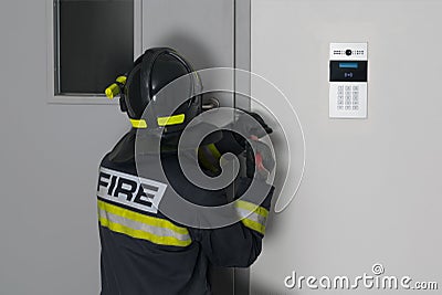 A firefighter tries to open the iron front door with a crowbar Stock Photo