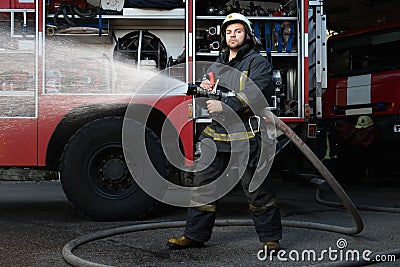 Firefighter with water hose near truck Stock Photo