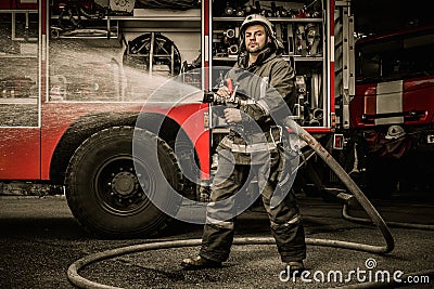 Firefighter with water hose near truck Stock Photo