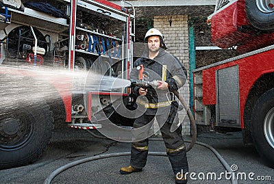 Firefighter with water hose near truck Stock Photo