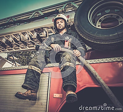 Firefighter with water hose near truck Stock Photo