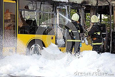 Firefighters extinguish burning bus with foam Stock Photo