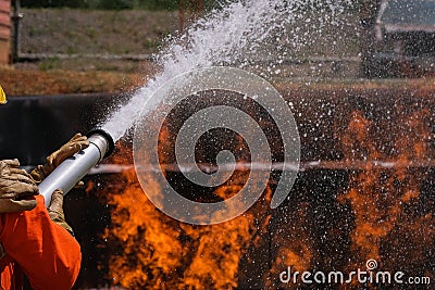 Firefighters extinguish the fire with chemical foam coming from the fire engine through a long hose Stock Photo