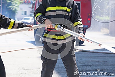 Firefighters holding firehose to extinguish fire Stock Photo