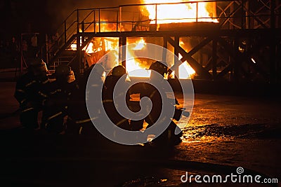 Firefighters kneeling in preparation to fight fire in firefighting exercise Editorial Stock Photo