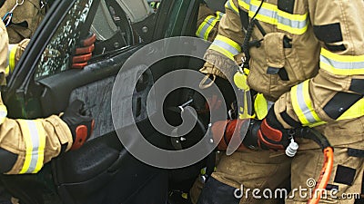 Firefighters using jaws of life to extricate trapped victim from the car Stock Photo