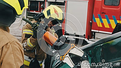 Firefighters using jaws of life to extricate trapped victim from the car Stock Photo