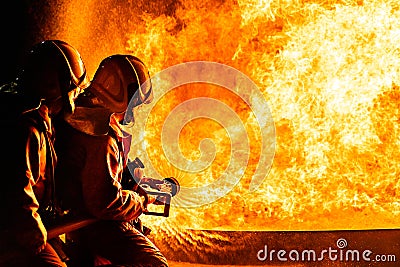 Firefighters use twirl water fog spraying down fire flame Stock Photo