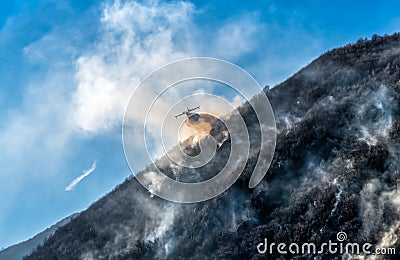 Firefighting Aircraft dropping the water for fighting a fire on mountain Stock Photo