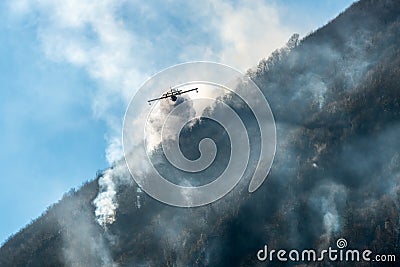 Firefighting Aircraft dropping the water for fighting a fire on mountain above Lake Ghirla in Valganna, province of Varese, Italy Stock Photo