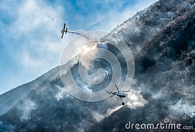 Firefighting Aircraft and Helicopter dropping the water for fighting a fire on mountain Editorial Stock Photo