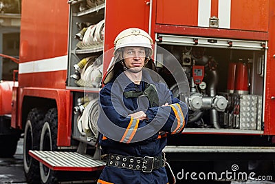 Fireman firefighter in action standing near a firetruck. Emer Stock Photo