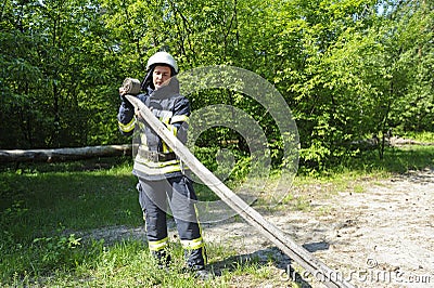 Fireman folding a hose up after fire fighting Editorial Stock Photo