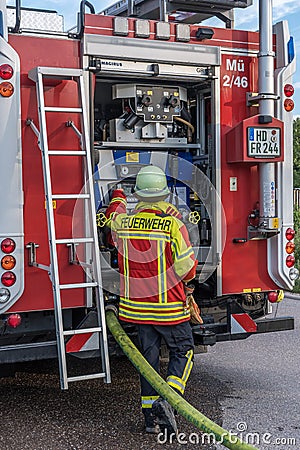 Fireman of German voluntary fire department in front of the open back side of Editorial Stock Photo