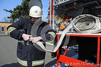 Fireman joining syringe of a water cannon to a hose before firefighting Editorial Stock Photo