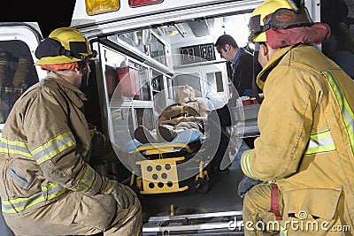 Fireman Looking At Patient And EMT Doctor Stock Photo